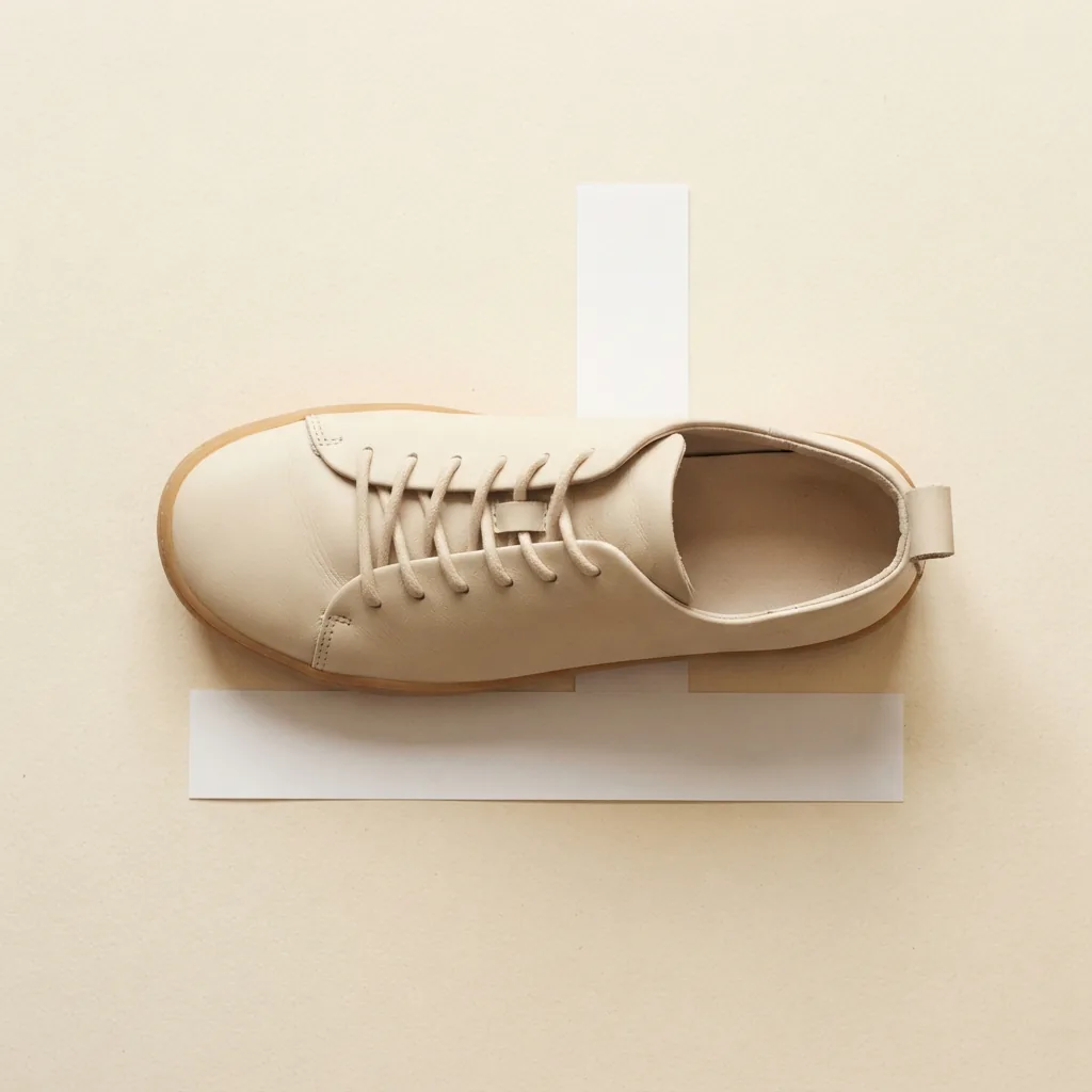 Overhead view of one women's shoe next to a paper size ruler on a pale surface